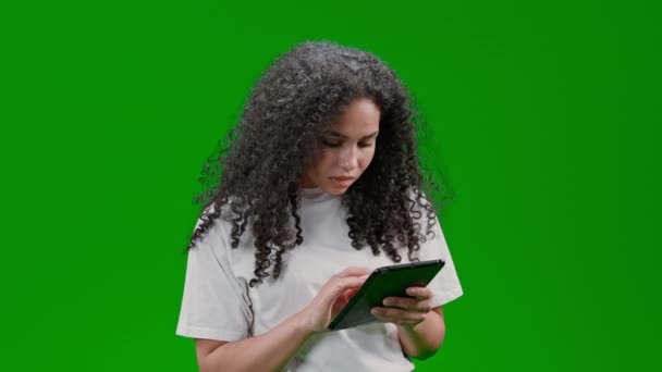 データを入力したり 買い物リストを作るデジタルタブレットを保持白いシャツを身に着けている巻き長い髪の毛を持つ女性緑の画面に隔離 — ストック動画