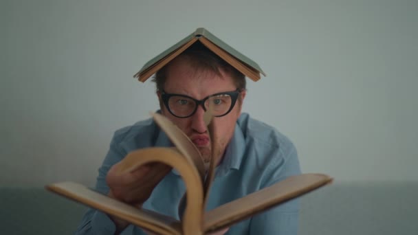 Hombre Lleva Gafas Hojas Través Libro Hace Caras Mirando Cámara — Vídeos de Stock