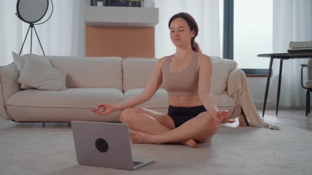 在网上与教练一起练习瑜伽的女人坐在地板上 一边笑着一边看展览 — 图库视频影像