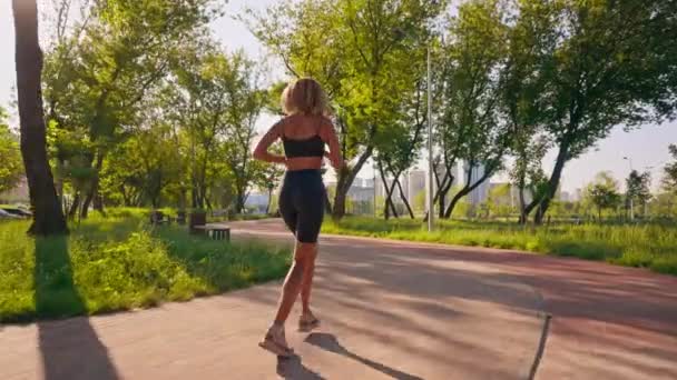 ブロンドのカーリーヘアを着たリーン女性 朝の都市景観アクティブスポーツライフスタイルでアクティブなジョギング — ストック動画