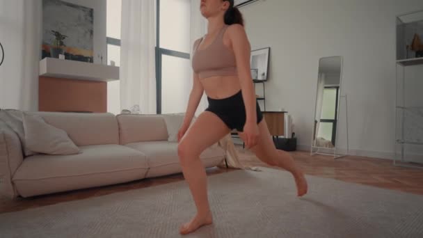 若いブルネット練習ヨガ屋内スローモーション女性は アパートで運動フィットネスを行います — ストック動画
