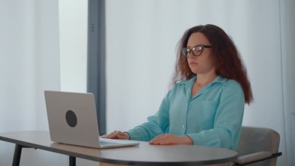 一个女人坐在桌旁 全神贯注地在笔记本电脑上工作 免版税图库视频片段