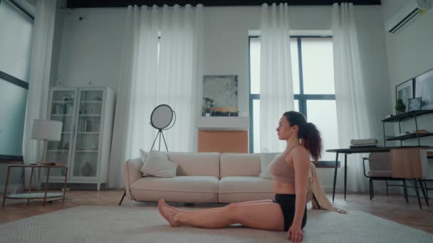 在一个典型的客厅里 一个女人坐在地板上 她平静地坐着 放松地伸展练习瑜伽 免版税图库视频片段
