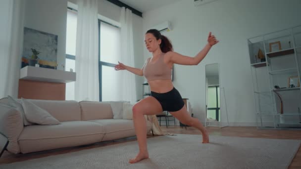 有人看到一个女人在客厅里练习瑜伽姿势 她专注于身体的平衡和呼吸 同时优雅而有力地保持姿势 免版税图库视频