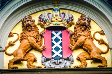 Amsterdam 'ın arması, merkezi bir kırmızı kalkanın etrafını saran iki azgın aslanı içeriyor. Kalkanda üç altın taşlama (x şeklinde haçlar) yüklü siyah bir şerit bulunur. Kalkanın tepesinde...