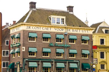 A charming cafe in Amsterdam with green and white striped awnings. The building itself could be a historic landmark, adding architectural interest to the scene. clipart