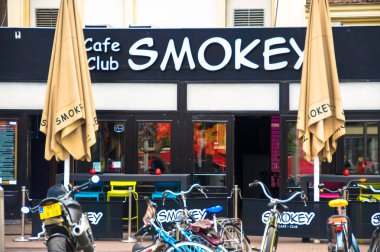 Amsterdam mı? Renkli bisikletler siyah tentelerle korunan Cafe Smokey 'nin kırmızı duvarlarına karşı düzgünce diziliyorlar. Bisikletçiler için popüler bir nokta, Amsterdam 'ın hem yeşil taşımacılığa olan sevgisini somutlaştırıyor