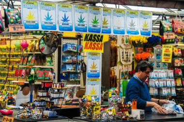 Amsterdam 'ın esrar dispanserinde kenevir tohumu, Orange Skunk ve Mor Güç türleri, kadınlar için yüksek kaliteli esrar ve Laddrak marka ürünler bulunuyor. Bu fiş tarzı reklam belki de...