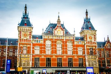 Amsterdam Centraal İstasyonu, saat kulesi olan büyük bir kırmızı tuğla bina, Hollanda, Amsterdam 'da bir ulaşım merkezi ve bir dönüm noktasıdır..