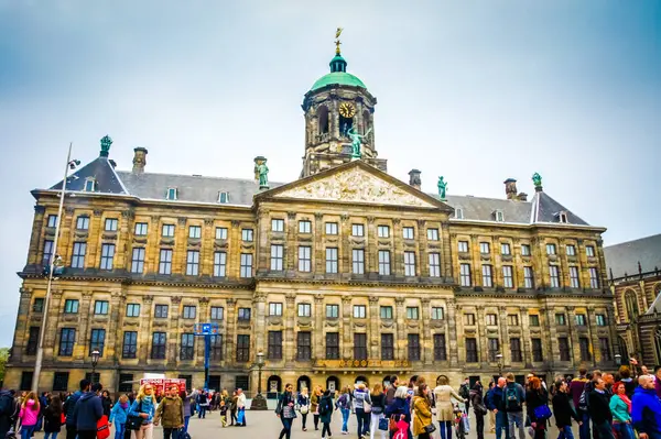 Stock image Amsterdam's bustling city center unfolds in Dam Square, a large open space paved with red brick. Crowds gather amidst 17th-century buildings, making it a popular tourist destination.