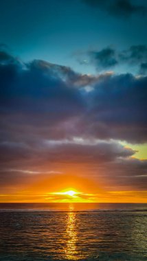 Sunset over calm ocean. Golden sun dips below horizon, casting long reflections on water. Peaceful scene evokes feelings of tranquility and wonder. Cook Islands. clipart