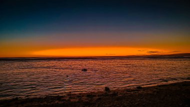 Cook Adaları 'nda canlı günbatımına karşı tek kişilik bir figür duruyor. Doğanın nefes kesici sanatının ortasında huzurlu bir tefekkür..