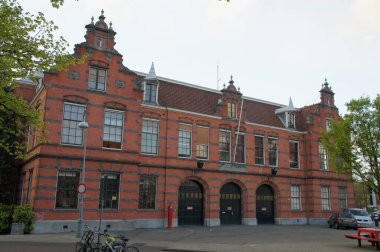 Amsterdam's red brick building with a large metal door could be a historic fire station or a business with convenient bike parking. clipart