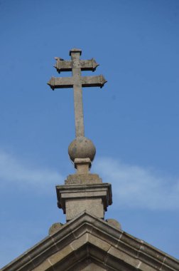 Portekiz, Braga 'da canlı bir mavi gökyüzüne karşı, karmaşık bir şekilde oyulmuş, yıpranmış bir taş haç duruyor. İnancın ve dayanıklılığın, tarihin ve mimarinin ebedi sembolü..