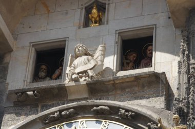 Prag Astronomik Saati, ortaçağ taş işçiliğinin ve karmaşık detayların başyapıtı. Dini figürler saati süslerken, altın bir horoz rüzgar gülünün tepesinde. Bir saat içinde elçiler gelir.,