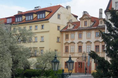 Prag binaları. Kemerli camları ve dekoratif unsurları olan barok bir cephe. Ağaçlar ve lambalar önde. Çek Cumhuriyeti başkentinin mimari mücevheri.