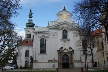 Strahov Manastırı, Çek Cumhuriyeti. Beyaz cepheli ve iki kuleli barok mimari. Altın haç ve güneş amblemi, inancı ve ruhaniliği sembolize ederek binayı süslüyor. Manastır bir...