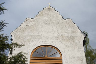 Kilise cephesindeki süslü alçı, dini figürleri tasvir ediyor. Girişin üzerinde ahşap çerçeveli yuvarlak bir pencere var, muhtemelen İncil 'den bir sahneyi resmediyor. Bu bir sembolik.