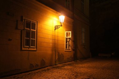 Eski fener Çek Cumhuriyeti 'nin karanlık sokaklarını aydınlatıyor. Cobblestone Caddesi ve eski binalar. Atmosferik ve gizemli. Tarih ve entrika anlayışı. Çek Cumhuriyeti.