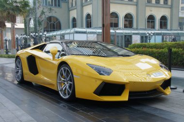 Dubai 'nin parlak gökdelenleri parlak sarı bir Lamborghini Aventador için zemin oluşturur. Spor arabaların keskin çizgileri ve parlak renk ipuçları lüks ve güç için bunu olası bir reklam haline getiriyor.