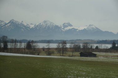 Germany, Munich. Snow-capped mountains are reflected in a still lake, creating a peaceful mountain landscape. The scene is a place of tranquility and beauty, a mirror reflecting nature's grandeur. clipart