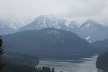 Almanya, Münih. Bulutlu bir gün, karlı dağların arasına kurulmuş sakin bir göl üzerinde sakin bir atmosfer oluşturur. Sahne huzur ve sükuneti çağrıştırıyor, mükemmel bir kaçış. Alternatif olarak,