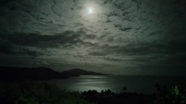 Hamilton Adası 'nda gece parıltısı: Dolunay sakin okyanus boyunca parlak bir yol açar ve büyülü bir parıltı yaratır. Huzurlu gece gökyüzü bu sakin ada sahnesini tamamlıyor..