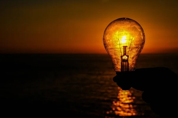 Stock image Energy Concept Light Bulb and Sun Setting on the Atlantic Ocean