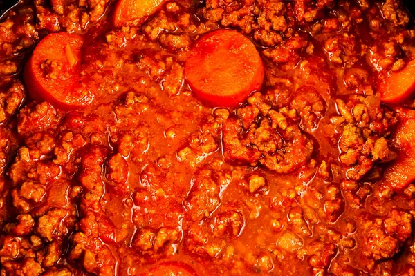 A pot of chili with meat and carrots. The chili is hot and spicy