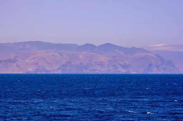 Oceano Calmo Céu Azul Montanhas Fundo Estão Cobertas Neve Imagens De Bancos De Imagens Sem Royalties