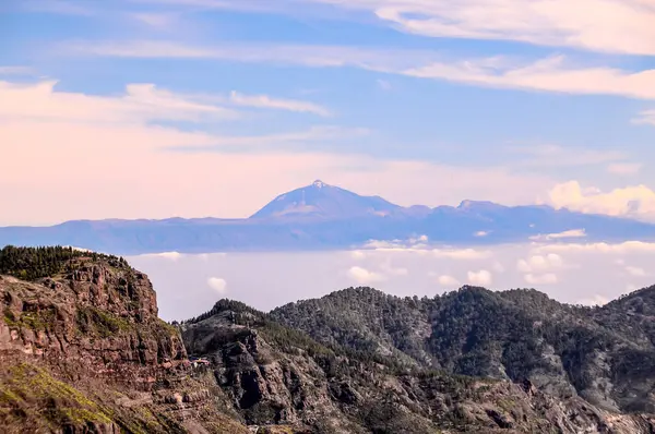 Stock image A mountain range with a large mountain in the background. The sky is clear and blue with a few clouds, real image