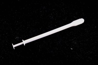 A white object with a pointed end is on a black background. The object is long and thin, and it is a medical instrument. Concept of precision and focus clipart