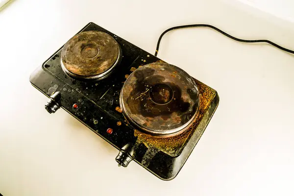 stock image A black stove top with a burnt pot on it. The stove is old and dirty