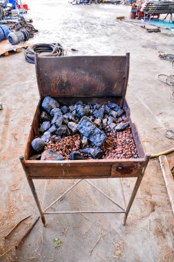 A pile of rocks sits on top of a grill. The grill is old and rusty, and the rocks are black and grey. The scene is somewhat bleak and uninviting, with the grill and rocks seeming to be abandoned clipart