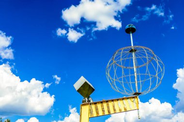 A large globe is on top of a pole with a blue sky in the background. The globe is surrounded by a metal mesh, giving it a somewhat industrial appearance. Concept of curiosity and wonder clipart