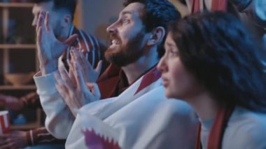 Futbol taraftarları TV 'de program maçı izlerken spor takımı için tezahürat yapıyorlar ve olumlu sonuçlar için yüksek sesle umut ediyorlar. Gergin arkadaşlar maçta kaybettikleri için hayal kırıklığına uğradılar.