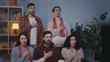 Kendine güveni tam, heyecanlı genç melez arkadaşlar evde TV karşısında oturup maç izlemeden önce vatansever ilahiler söylüyorlar. Sevindiler, alkışladılar.