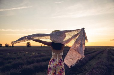 Gün batımında lavanta tarlasında atkısı olan bir kadın..