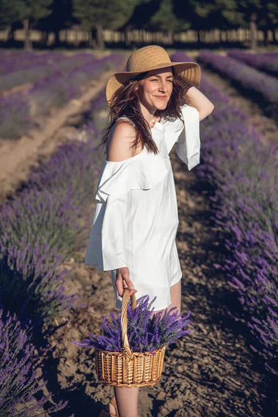 A woman with a basket and a pamela in a field of lavender.