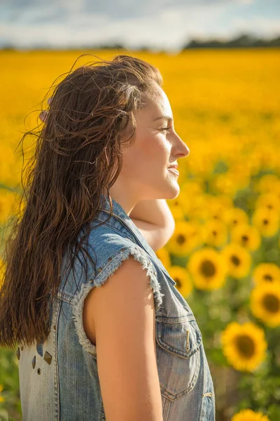 A young woman gazing at the sun in a sunflower field