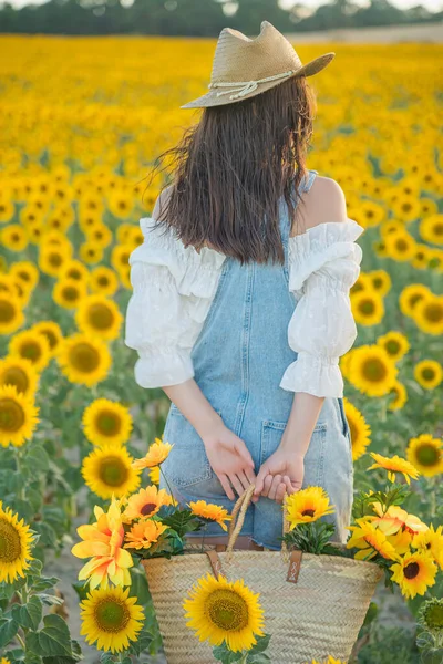 A woman with shady back in a field of sunflowers