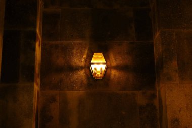 An antique iron lantern installed in a stone building