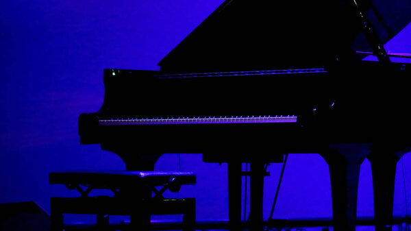 Гранд-пианино, поставленное на сцене тускло освещенного живого дома перед выступлением