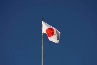 Mavi gökyüzüne karşı rüzgarda dalgalanan Japon bayrağı