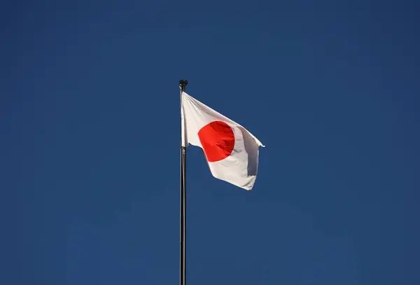 Mavi gökyüzüne karşı rüzgarda dalgalanan Japon bayrağı