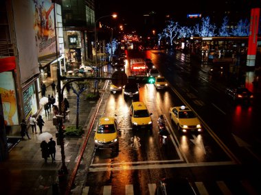 March 8, 2017, Taipei City, Taiwan A beautiful scene on Songgao Road in Xinyi District on a rainy day, with car headlights, illuminated signs and illuminated tree lights sparkling clipart