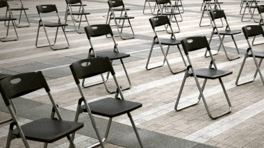 Folding chairs lined up at the event venue in the square clipart