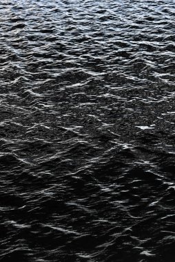 Arka planda tekrarlanan dalgalanmalarla dolu güzel bir su yüzeyinin yakın plan fotoğrafı.