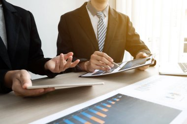 İki iş adamı ofiste iş grafiği ve planlama stratejisi, iş ve finans kavramını tartışıyor.