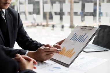 İki işadamı ofis odasındaki yatırımları planlamak için bir grafikte kazancı analiz ediyor. iş görüşmeleri ve planlama stratejisi.